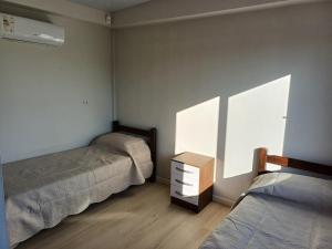 1 Schlafzimmer mit 2 Betten, einer Kommode und einem Fenster in der Unterkunft La Demorada, cómoda casa en entorno natural in Mercedes