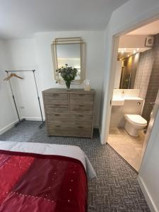 a bathroom with a dresser and a toilet and a mirror at Contemporary City Centre 3 bedroom apartment in Sheffield