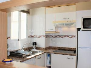 cocina blanca con fregadero y nevera en Apartament Cala Merced Alicante El Campello, en El Campello