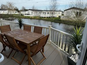 een houten tafel en stoelen op een terras met een rivier bij Inviting 6 Birth Lodge - Southview Skegness in Skegness
