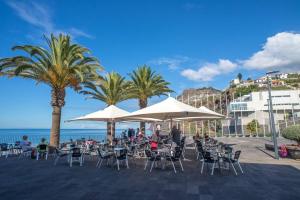 a group of people sitting in chairs under white umbrellas at 2 bedrooms appartement with wifi at Camara De Lobos 4 km away from the beach in Funchal