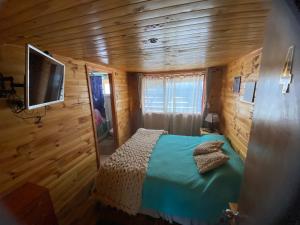 a bedroom in a log cabin with a bed and a television at Hospedaje Alto Palena de Puerto Cisnes in Puerto Cisnes