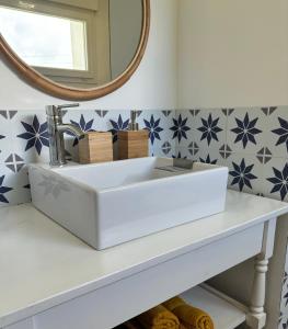 ein Badezimmer mit einem weißen Waschbecken und einem Spiegel in der Unterkunft Les gîtes du manoir de Port Cadic in Rédené