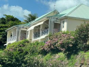 a white house on top of a hill with flowers at Zabana Lodge, dans un jardin tropical avec piscine in Saint-Claude