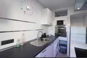 eine weiße Küche mit einer Spüle und einer Mikrowelle in der Unterkunft 2 bedrooms appartement with wifi at Frigiliana 7 km away from the beach in Frigiliana