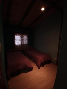a dark room with two beds and a window at Cabañas Don Carlos in El Hoyo
