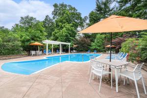 einen Pool mit einem Tisch, Stühlen und einem Sonnenschirm in der Unterkunft Howard Johnson by Wyndham Traverse City in Traverse City