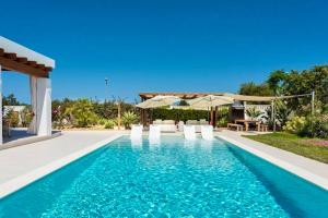 a pool with chairs and umbrellas next to a house at 4 bedrooms house with private pool terrace and wifi at Sant Josep de sa Talaia 3 km away from the beach in Sant Josep de sa Talaia