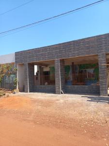a brick building with three windows and a dirt yard at Pousada Anayh, Nobres-MT, Vila Bom Jardim in Buracão