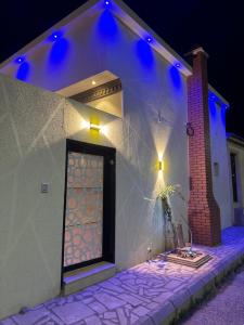 una casa blanca con una puerta con luces azules en لاڤانا en Unayzah