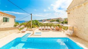 a house with a swimming pool next to a building at Villa Vicko in Sumartin