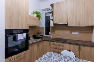 a kitchen with a black oven and wooden cabinets at Gyöngy Apartman in Pécs