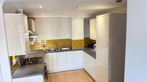 uma cozinha com armários brancos e um lavatório em Cosmo Suites em Bracknell