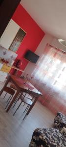 een eetkamer met een tafel en een rode muur bij B&B MANITO in Lavena Ponte Tresa