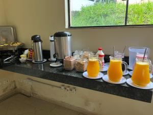 einer Theke mit zwei Tassen Orangensaft auf Platten in der Unterkunft Hotel Vila dos Pescadores in Aparecida