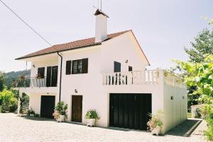 a white house with black doors and a balcony at 2 bedrooms house with shared pool enclosed garden and wifi at Ponte de Lima in Ponte de Lima