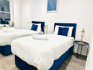 two beds in a room with blue and white at Town Center Luxury Apartment next to the Beach in Kent