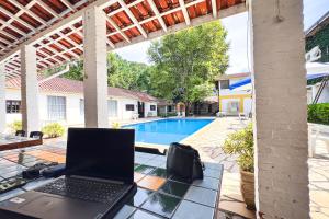 a laptop sitting on a table next to a swimming pool at VELINN Pousada Cesar in Santo Antônio do Pinhal