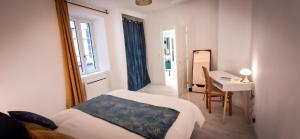 a bedroom with a bed and a table and a desk at L'Art Déco 3 étoiles Wifi, Netflix, Disney, Coeur de Bastide in Villefranche-de-Rouergue