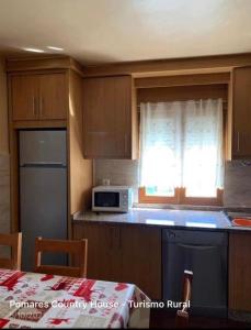 una cocina con armarios de madera y una ventana con microondas en Pomares Country House, en Melgaço