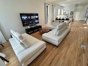 sala de estar con sofás blancos y TV de pantalla plana en Luxe Spacious SFH in Bucktown with Secure Parking, en Chicago