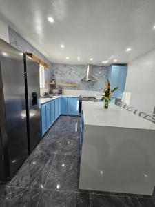 a kitchen with blue cabinets and a stainless steel refrigerator at Casa Margarita in First Bight