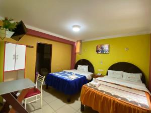 um quarto com duas camas e uma mesa em HOTEL TURISTICO EL OSCAR em Cutervo