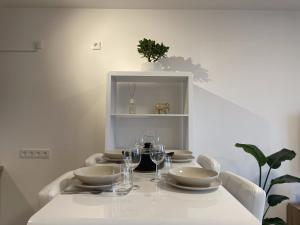 een witte tafel met borden en wijnglazen erop bij Luxurious and stylish apartment at BER Airport in Schönefeld