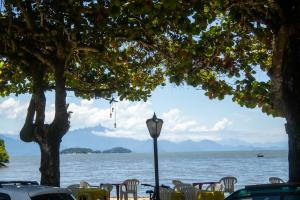 a street light in front of a lake with chairs and a tree at Encanto Paraty Beach in Paraty +49 photos