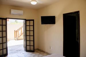 una stanza con una televisione sul muro e una porta di Encanto Paraty Beach a Parati