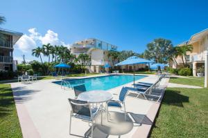 uma piscina com cadeiras e uma mesa ao lado de um edifício em Cayman Reef Resort #52 em George Town