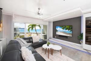 a living room with a black leather couch and a tv at Grape Tree Condo #10 in George Town