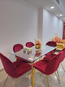 a dining room with a glass table and red chairs at Luxury Apartment - Beach Tower 2 in Sharjah