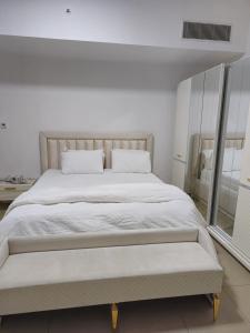 a white bedroom with a large bed and a window at Luxury Apartment - Beach Tower 2 in Sharjah