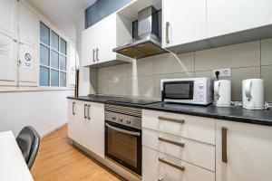 a kitchen with white cabinets and a microwave at Rooms Jardín Botánico in Valencia