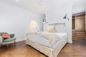 a white bedroom with a bed and a chair at Sunlit and Spacious Apt in the Heart of the East in Sydney