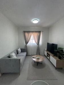 een woonkamer met een bank en een tv bij Cozy apartment in Carlswald in Midrand