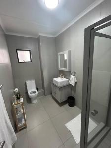 een badkamer met een toilet, een wastafel en een douche bij Cozy apartment in Carlswald in Midrand