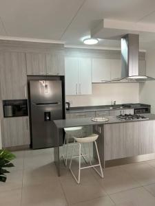 een keuken met een koelkast en een aanrecht met krukken bij Cozy apartment in Carlswald in Midrand
