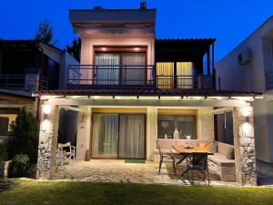 a house with a patio with a table and chairs at villa ATHINA in Kriopigi