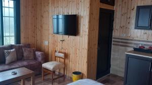 salon z kanapą i telewizorem na ścianie w obiekcie Rosemary Huts w mieście Adżlun