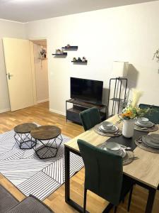 een woonkamer met een tafel en stoelen en een televisie bij Charmant Appartement à Metz in Metz