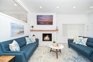 een woonkamer met twee blauwe banken en een open haard bij Brand new Lower unit on the Beach with Patio and Firepit in Newport Beach