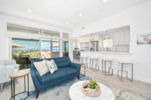 een woonkamer met een blauwe bank en een keuken bij Brand new Lower unit on the Beach with Patio and Firepit in Newport Beach
