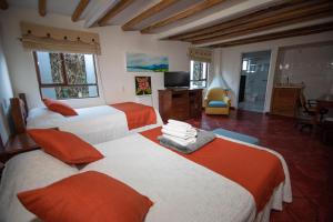 - une chambre avec 2 lits orange et blanc dans l'établissement Portal de las Flores, Alojamiento Rural, à Chía