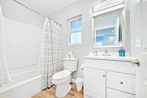 a white bathroom with a toilet and a sink at Cozy 3 Bedroom Across from Playground on the Beach in Newport Beach +17 photos