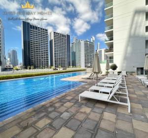 a pool with lounge chairs and umbrellas next to buildings at Reva residence suite burj Khalifa view ,Kings in Dubai