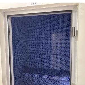 a glass shower door with blue tile in a bathroom at Reva residence suite burj Khalifa view ,Kings in Dubai