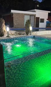 a swimming pool with green water at night at LA MANUELA CASA 1 in Pereira