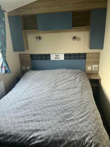 a bedroom with a bed with a blue headboard at Cjs family caravans in Ayr